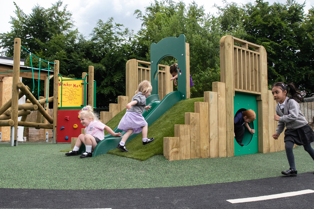 Children playing on EYFS equipment in outdoor EYFS area.