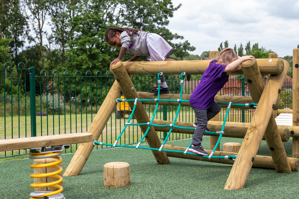 Children climbing over a EYFS trim trail installed on Wet Pour Rubber Playground Surface